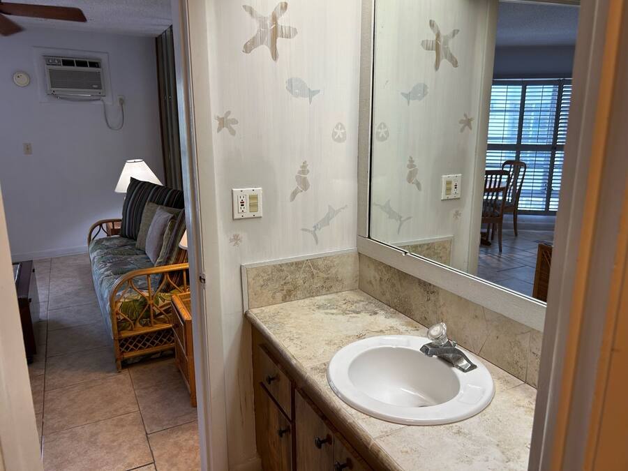 Un baño con lavabo blanco, espejo y zona de ducha.