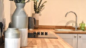 A kitchen with a wooden countertop, a stainless steel range hood, a sink, and a green soap dispenser. - *Penthouse Luxury Apartment 2min to Carlisle City (Carlisle)