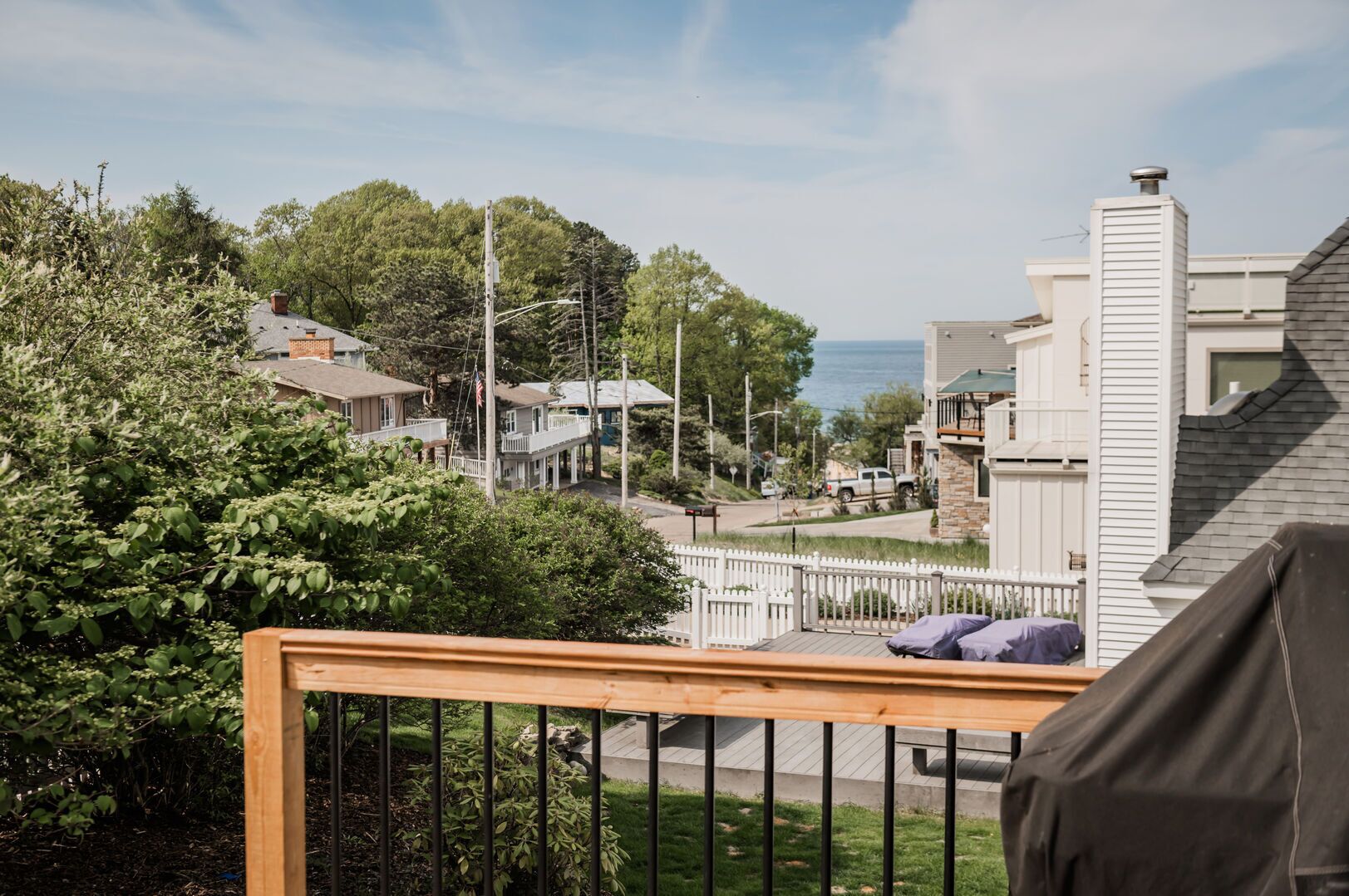 Et boligområde med huse, en træterrasse og havudsigt.