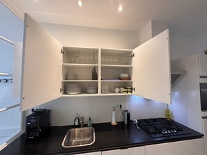 A kitchen with a built-in cabinet, a sink, a coffee maker, and a stove.
