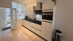 Une cuisine moderne avec des meubles blancs, un plan de travail noir et des appareils électroménagers en acier inoxydable.