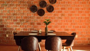 A dining area with a brick wall, a wooden table, four chairs, and decorative plates. - Valentin House, very spacious and cozy. (San Luis Potosí)