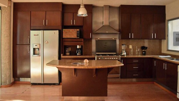 A modern kitchen with dark wooden cabinets, stainless steel appliances, and a central island. - Valentin House, very spacious and cozy. (San Luis Potosí)