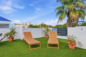 A rooftop terrace with two wooden lounge chairs, a hammock, and potted plants. - Marabey - Rooftop Condo Paradise (Ceiba,PR)