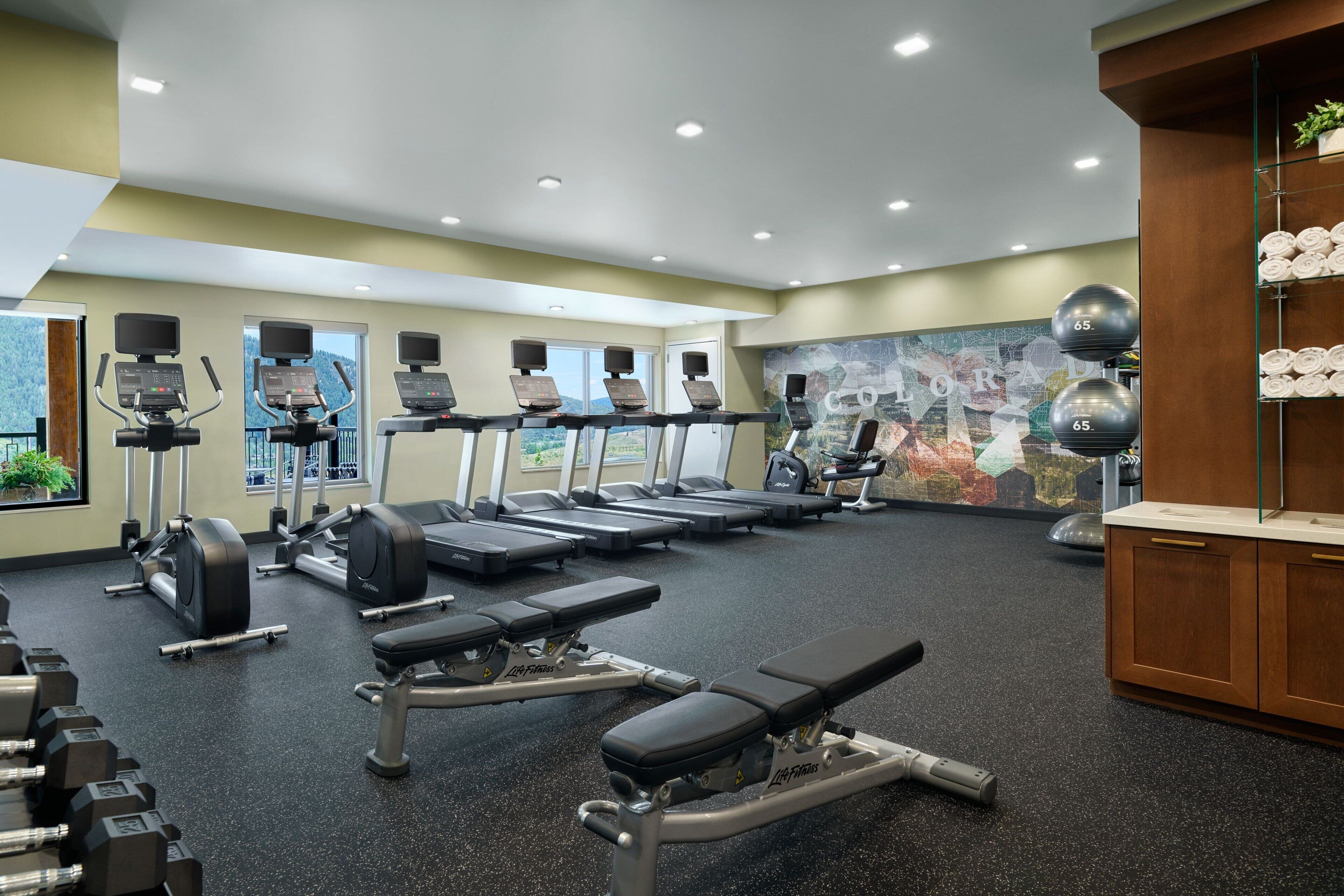 A gym with treadmills, weight machines, and dumbbells.