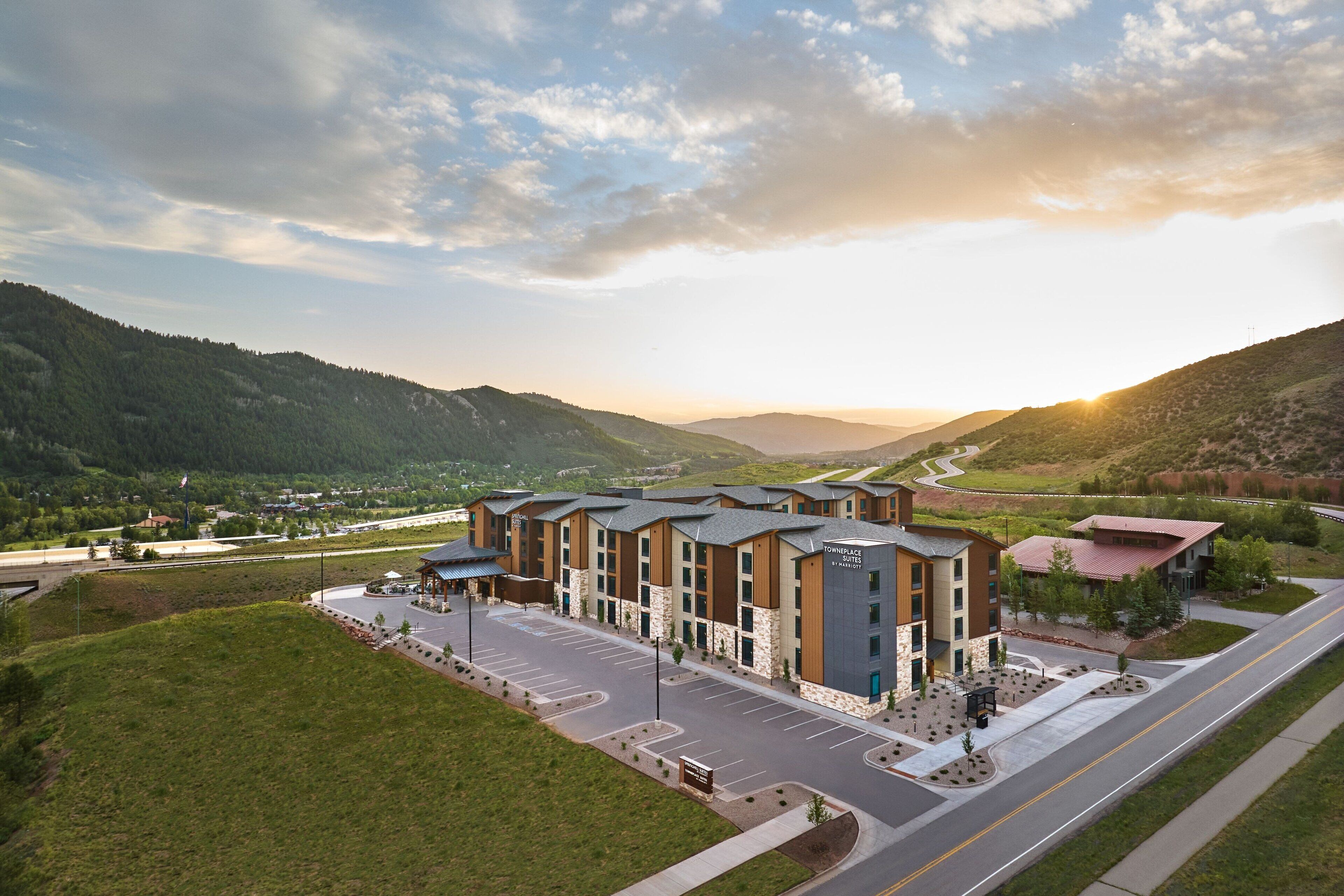 A modern hotel with a central courtyard, surrounded by lush green hills and a clear sky.