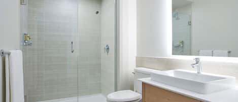 Ein modernes Badezimmer mit einer Duschkabine, einer weißen Toilette und einem Waschbecken mit Holzkonsolen.