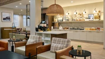 A modern hotel lobby with a seating area, a kitchen, and a bar.