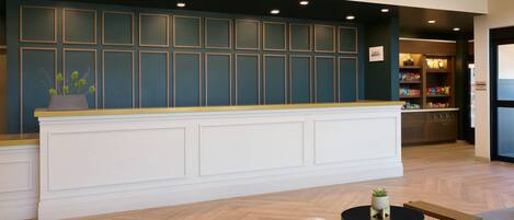 A reception area with a counter, seating, and a kitchen in the background.