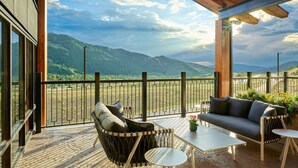 Un balcon doté d’un plafond en bois, d’un fauteuil rembourré, d’un canapé et d’une petite table.