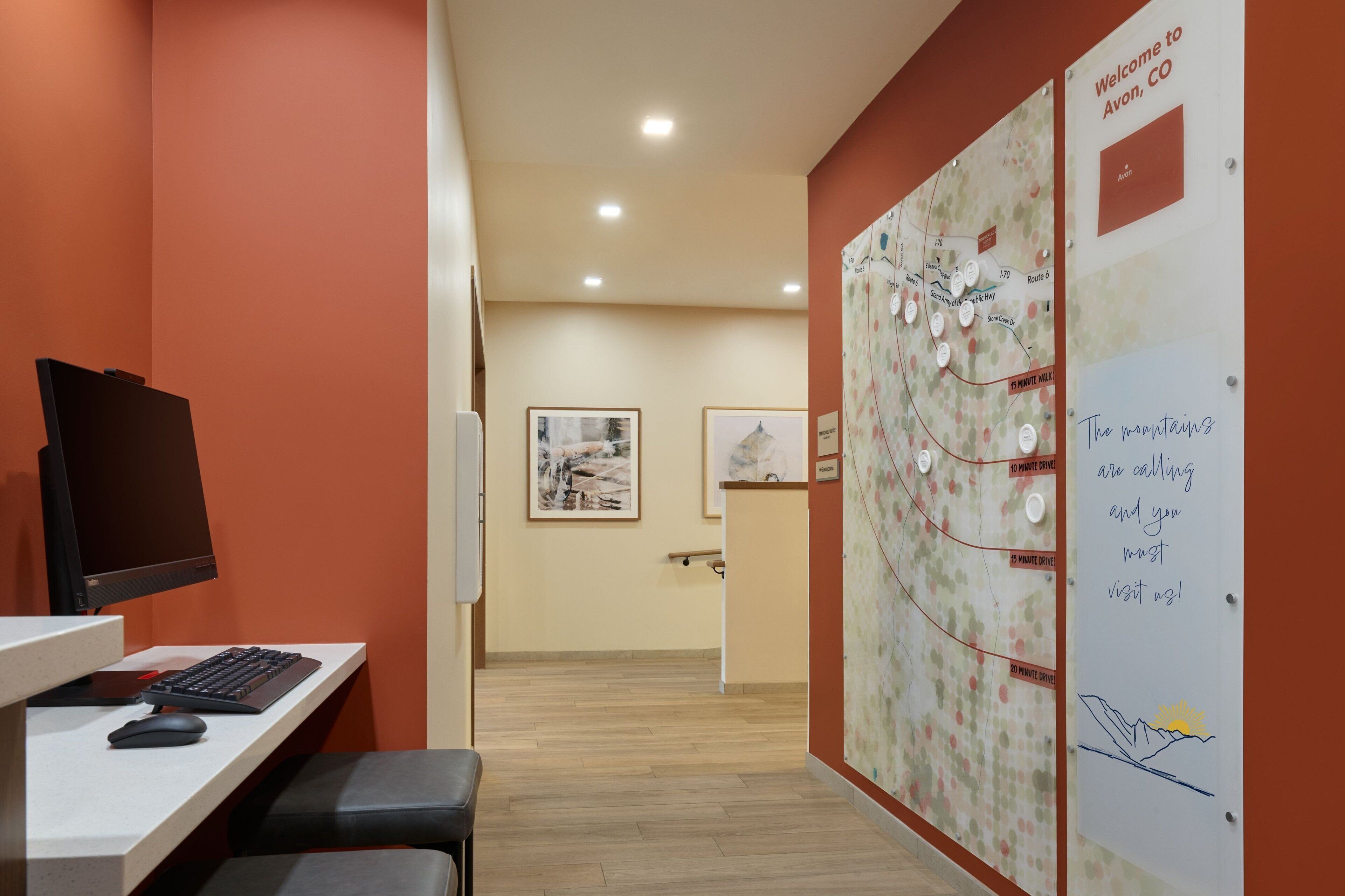 A reception area with a desk, computer, and seating. A large map and welcome sign are on the wall.