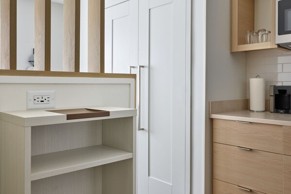 A modern bathroom with a white vanity, a mirror, and a wooden cabinet above the sink.