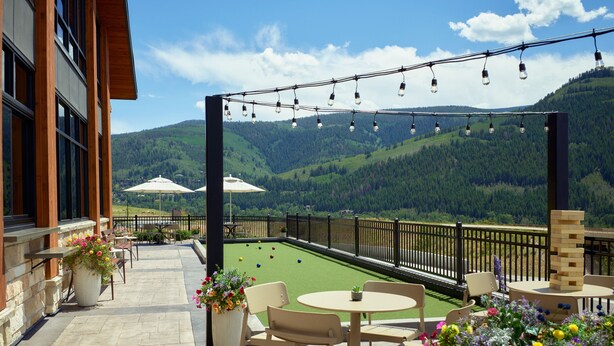 Eine Terrasse im Freien mit einem Croquetfeld, Sitzgelegenheiten und einer herrlichen Aussicht auf die Berge.