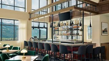 A restaurant with a bar area, multiple seating options, and large windows offering a mountain view.
