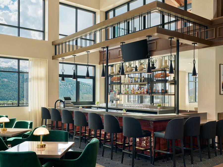 A restaurant with a bar area, multiple seating options, and large windows offering a mountain view.
