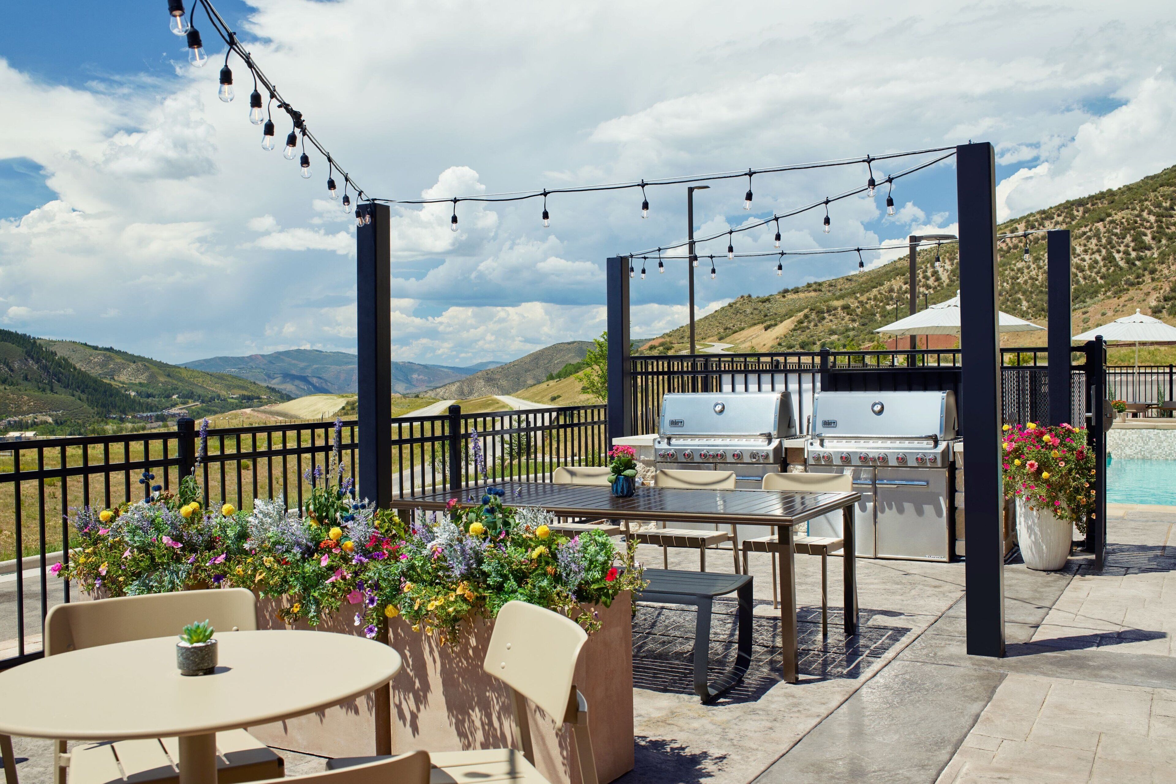 An outdoor patio with a grill, seating, and string lights.