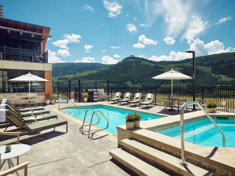 Une piscine sur le toit, agrémentée de chaises longues et de parasols, et offrant une vue panoramique sur les montagnes.