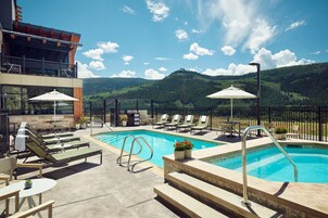 Una piscina al aire libre, sombrillas, sillones reclinables de piscina