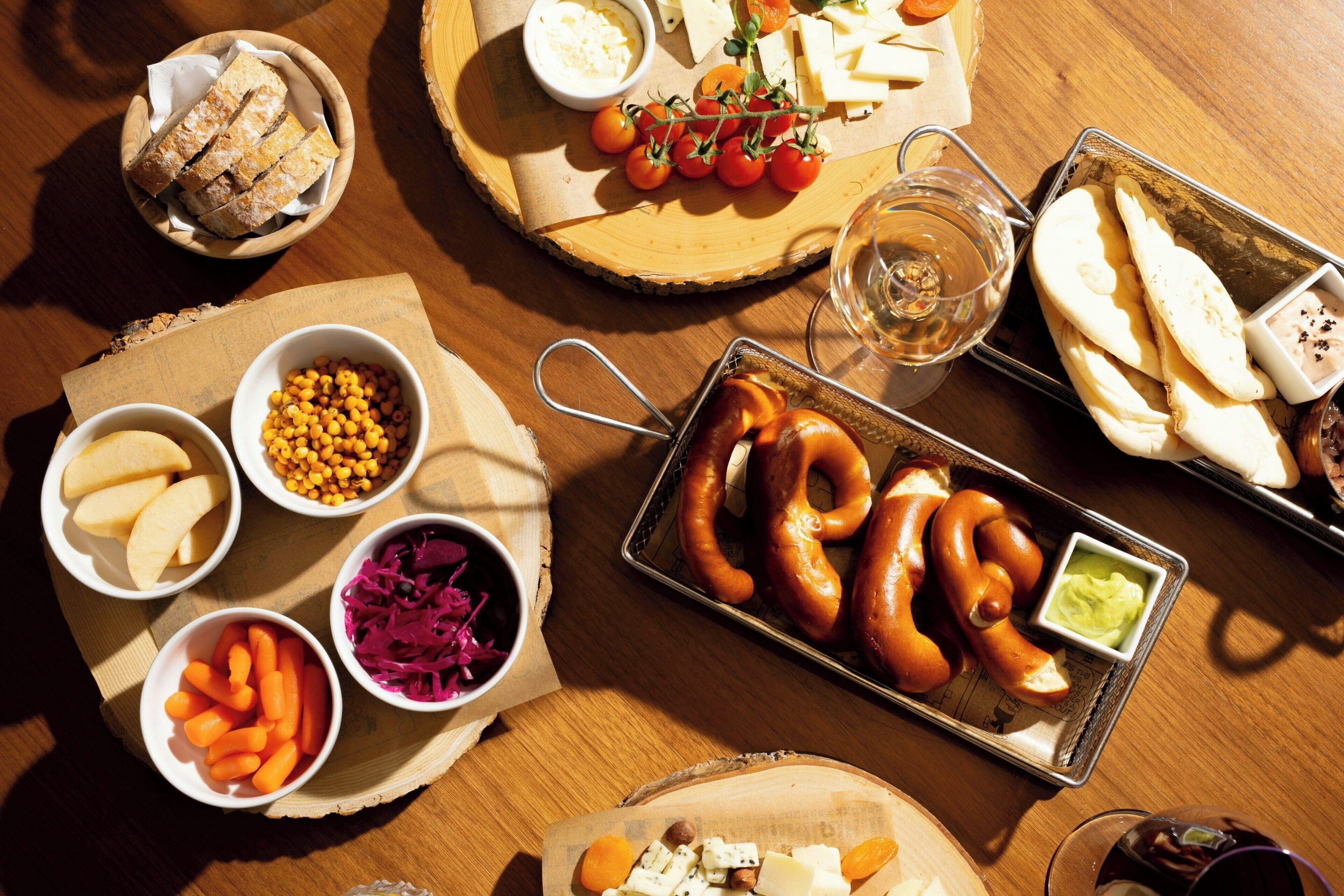 Een houten tafel met verschillende soorten eten en een metalen schaal met worstjes.