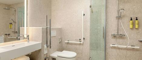 Un baño moderno con ducha envuelta en vidrio, un lavamanos blanco y un inodoro.