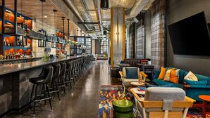 Zona de bar moderna con una barra larga, varios taburetes y un área de estar con sofá y sillones.