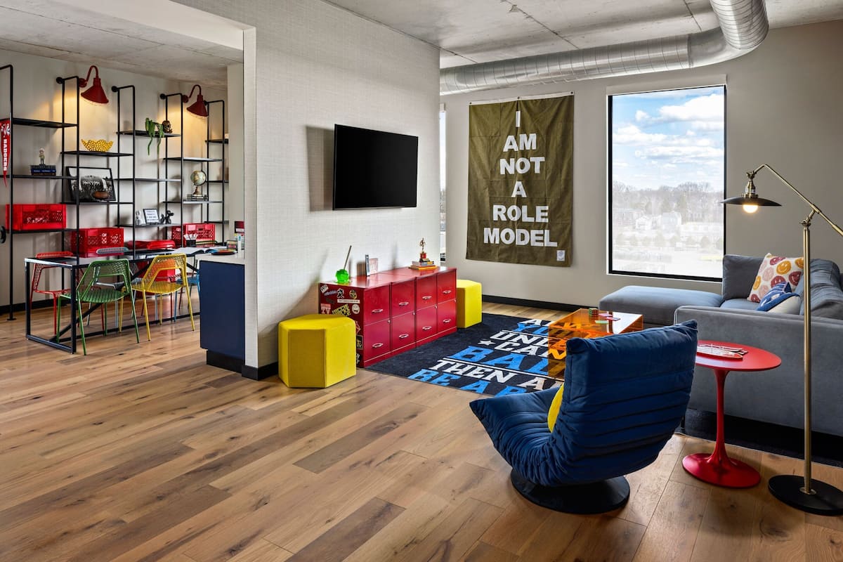A modern living room with a blue chair, a red table, and a large window.