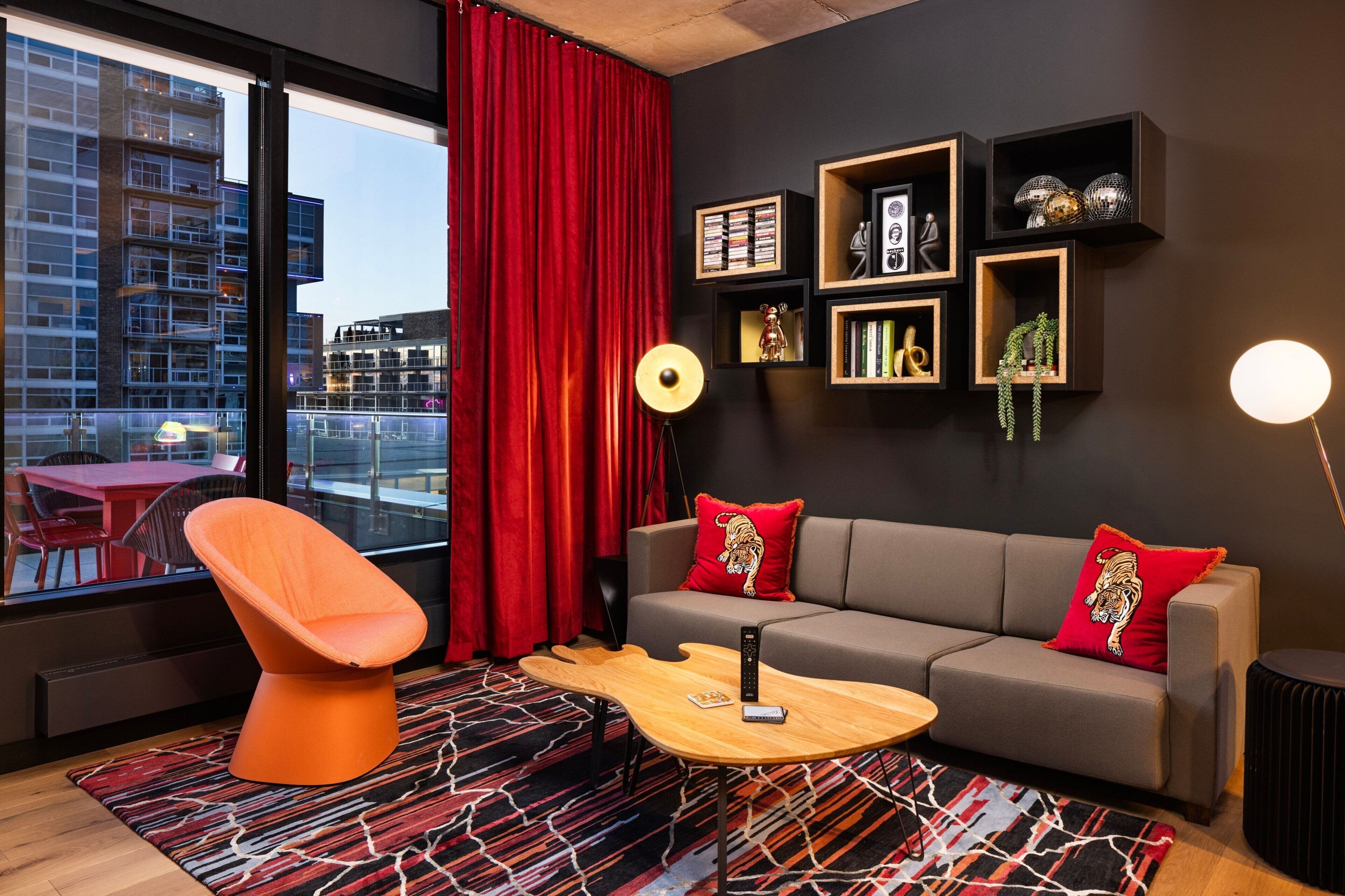 A modern living room with a sofa, a coffee table, and a red curtain.