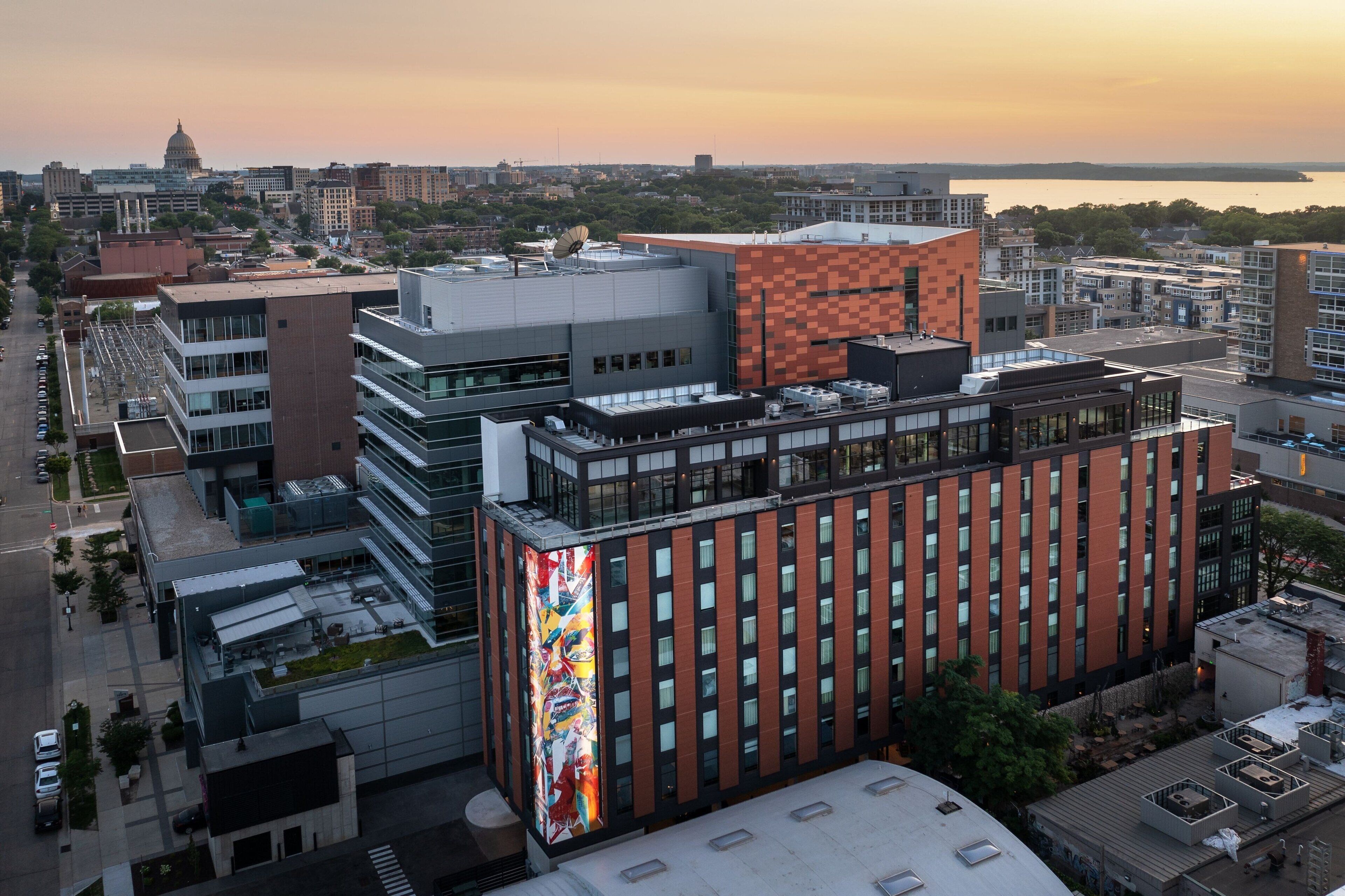 A modern building with a prominent glass facade and a large, colorful mural on one side.