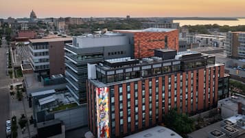 A modern building with a prominent glass facade and a large, colorful mural on one side.