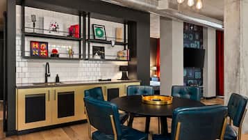 Una cocina moderna con encimera negra, salpicadero de azulejos blancos y sillas de cuero azul alrededor de una mesa de comedor negra.