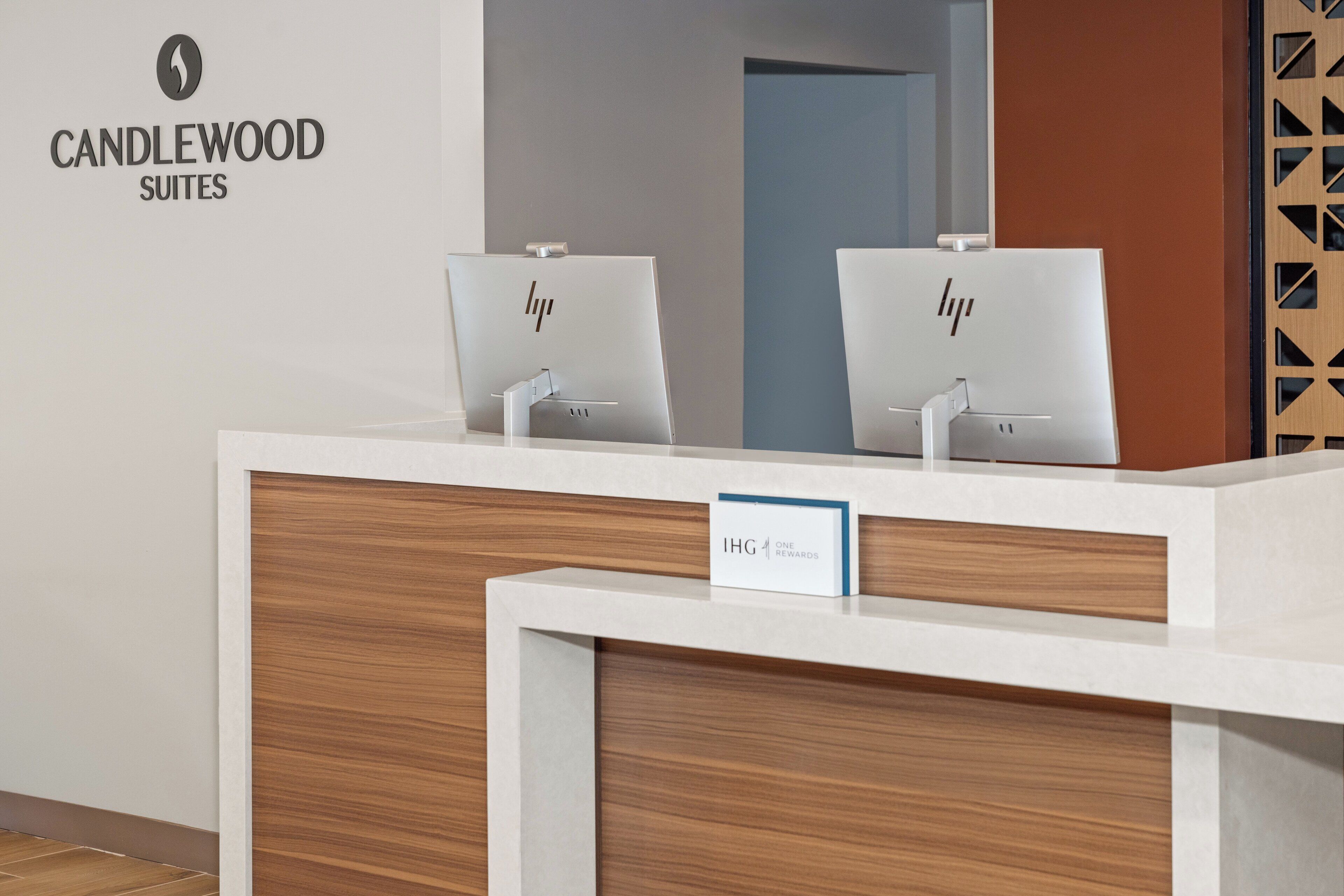 A reception desk with a sign reading "IHG ONE REWARDS" and a logo for Candlewood Suites.