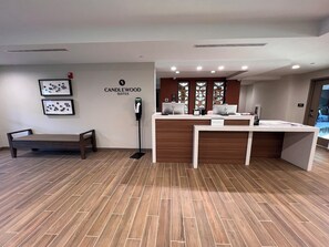 A reception area with a reception desk, a bench, and framed artwork on the wall.