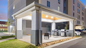 An outdoor patio area with a grill, seating, and a covered walkway. - Candlewood Suites Chattanooga East Ridge by IHG (Chattanooga)