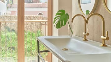 A bathroom with a white sink, gold faucets, and a large mirror.