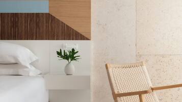 Un dormitorio moderno con una cama, una mesita de noche y una silla de fibras naturales.