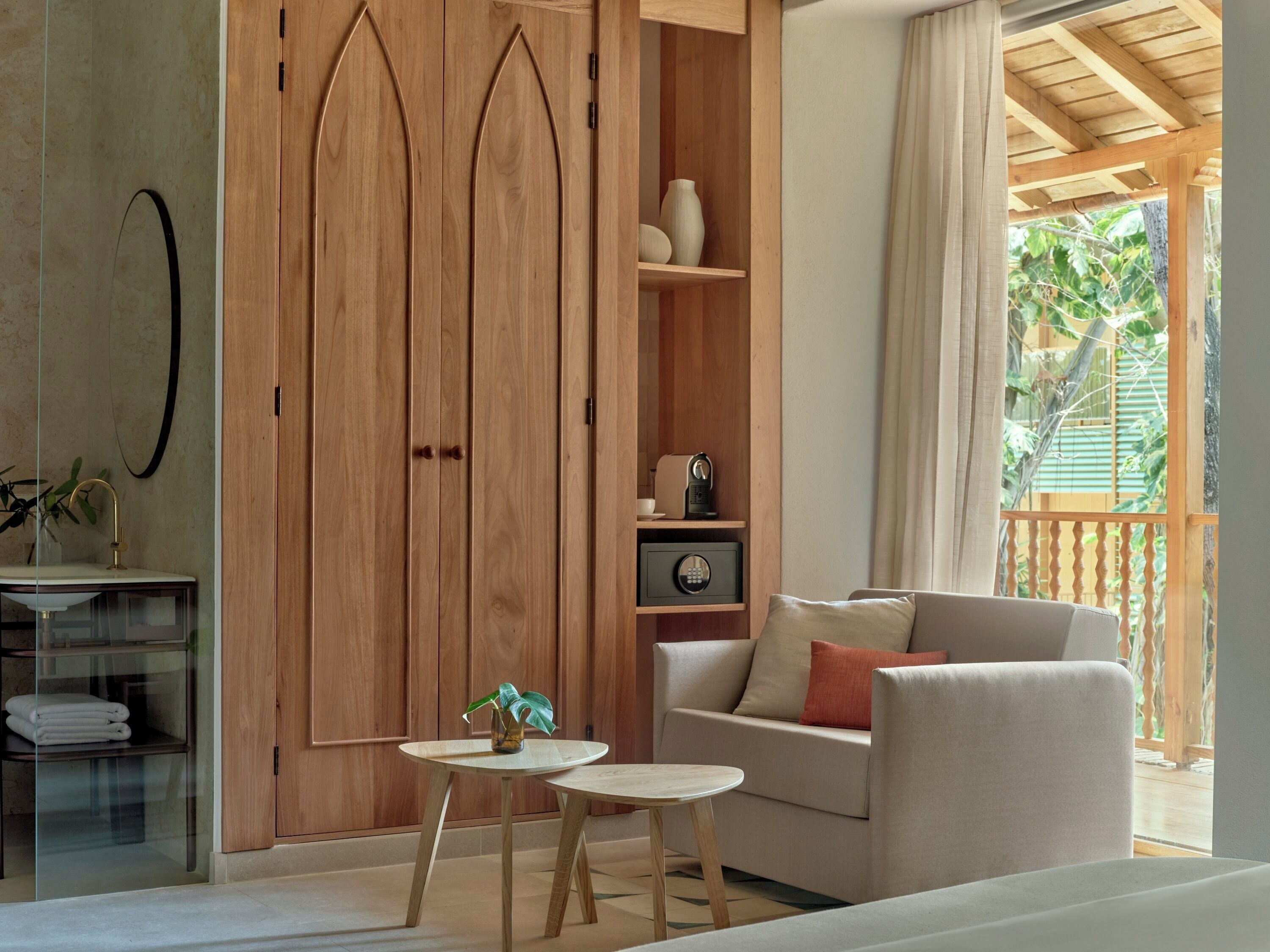 Una habitación moderna con un armario de madera, un sofá, una mesita y un aparador de vidrio.