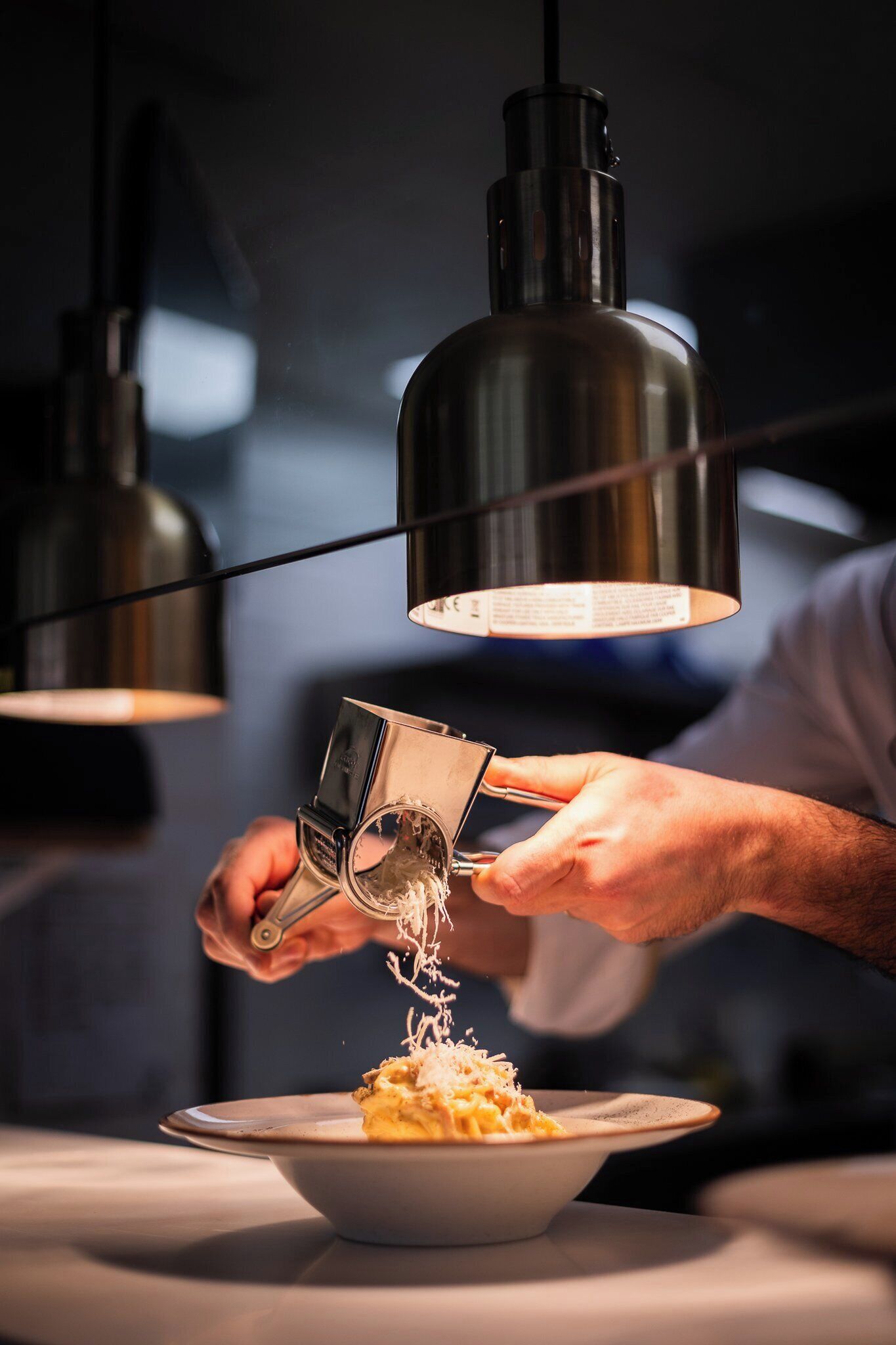 A person grating cheese over a dish.