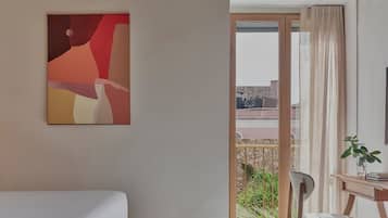 Een kamer met een bed, een bureau, een stoel, een raam met gordijnen en een schilderij aan de muur.