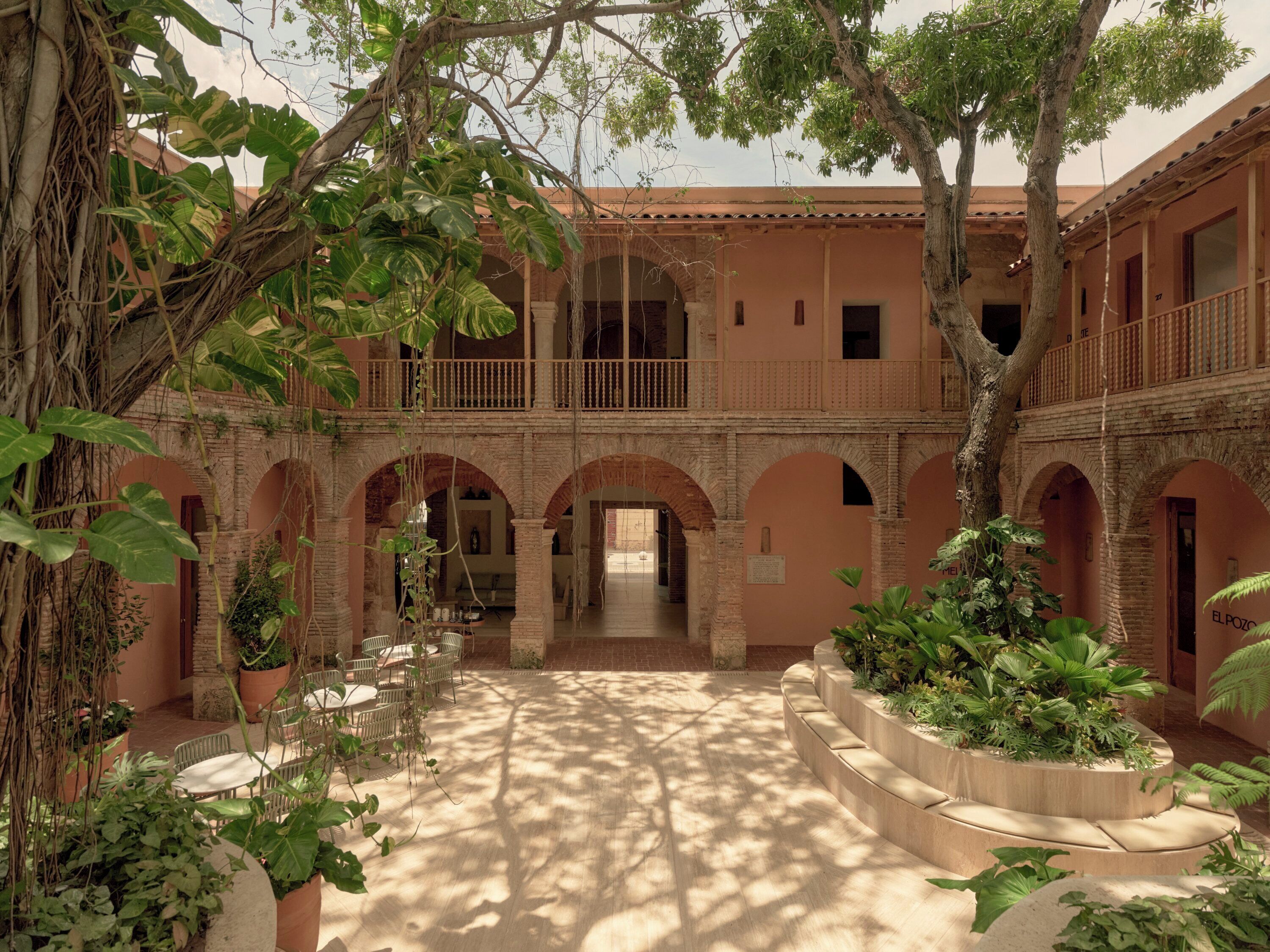 A courtyard with arches, potted plants, and a seating area.