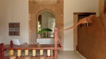 A dining area with a wooden table, stools, a brick wall, and a hanging plant.