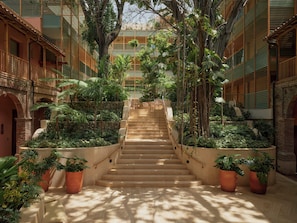 A staircase surrounded by lush greenery, leading to a covered area with a view of a building. - Kimpton Las Mercedes by IHG (Santo Domingo)