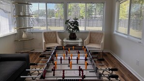 Un saló amb una taula de futbolí, dos sofàs, una taula de centre i una planta.