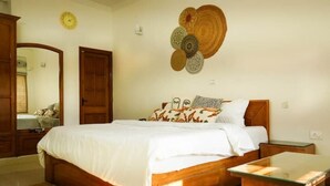 A bedroom with a wooden bed, a bedside table, and a wall-mounted decorative item. - Your getaway home with Ganga view in Rishikesh (Rishikesh)