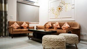 A living room with a brown sofa set, two matching ottomans, and a decorative wall piece. - Your getaway home with Ganga view in Rishikesh (Rishikesh)