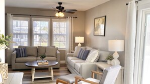 A living room with two sofas, a coffee table, a side table with lamps, and a ceiling fan. - Blue Cottage in the Bay - walk to beach and shops (Williams Bay)