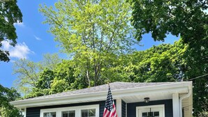 A small house with a front porch, a flag, and a mailbox. - Blue Cottage in the Bay - walk to beach and shops (Williams Bay)