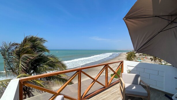 Une terrasse en bois offrant une vue sur la plage et l’océan.