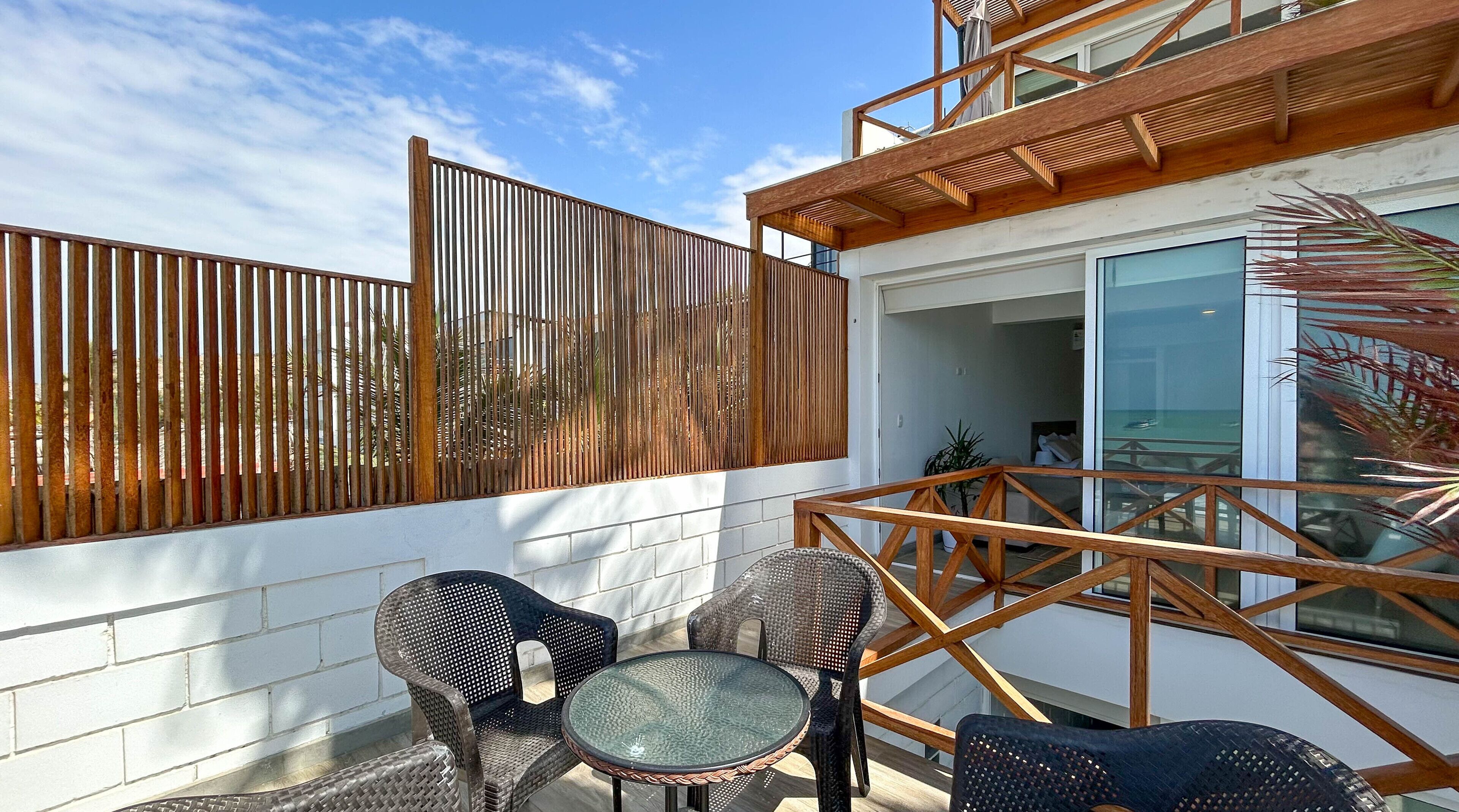 A balcony with wicker furniture and a wooden pergola.