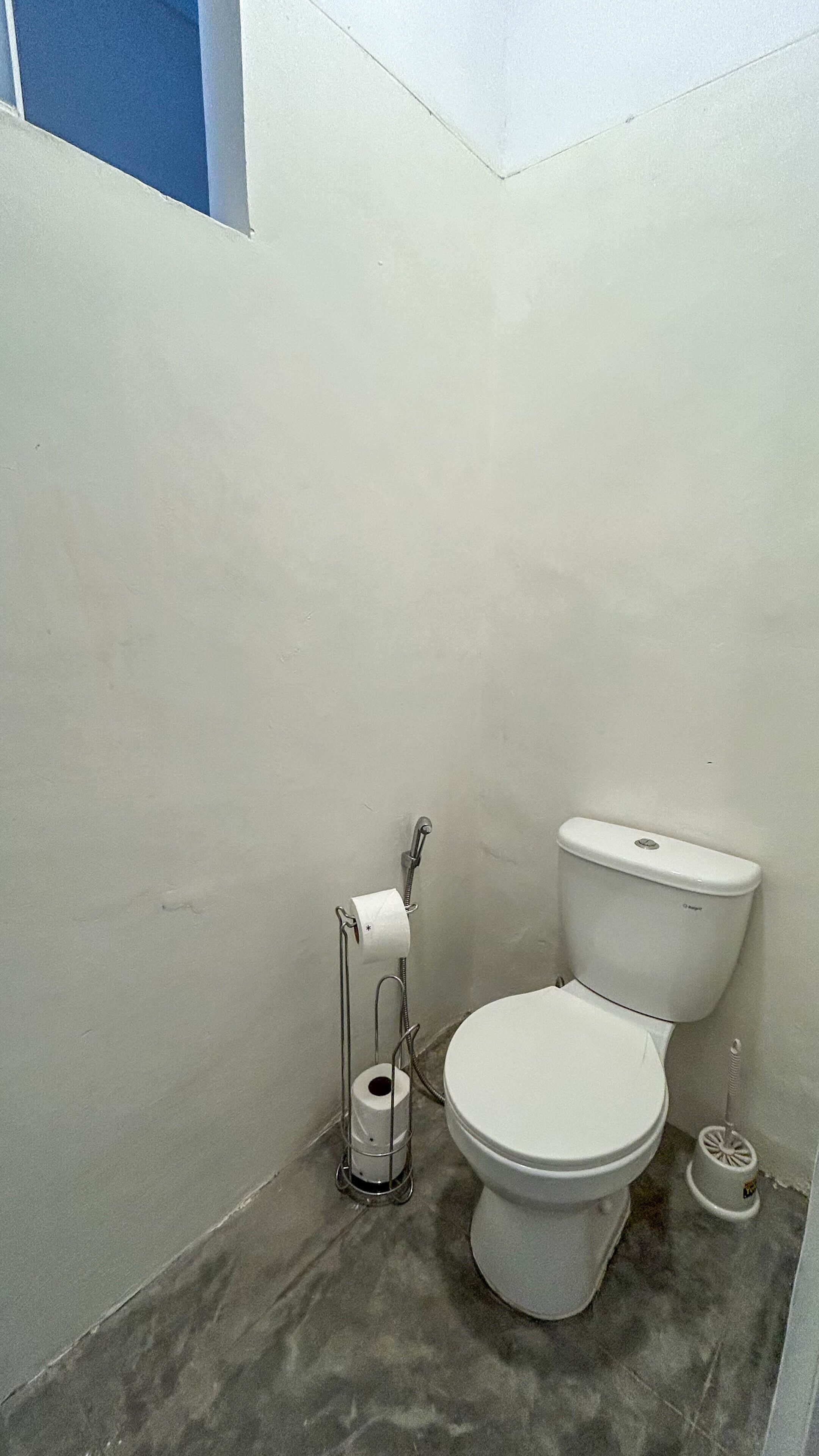 A small, basic bathroom with a toilet, a toilet paper holder, and a bidet.