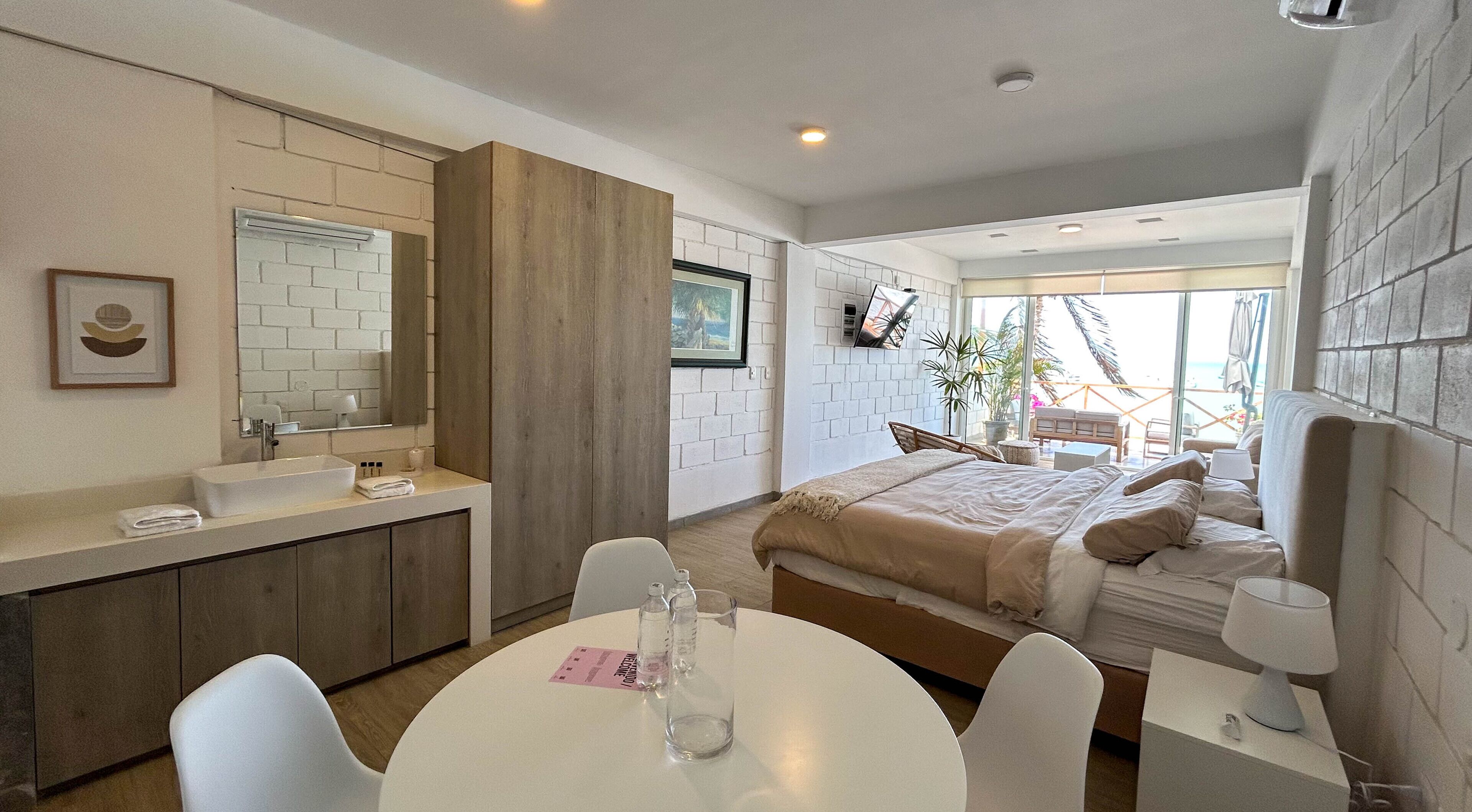 A modern bedroom with a bed, bedside table, and a round table with chairs.